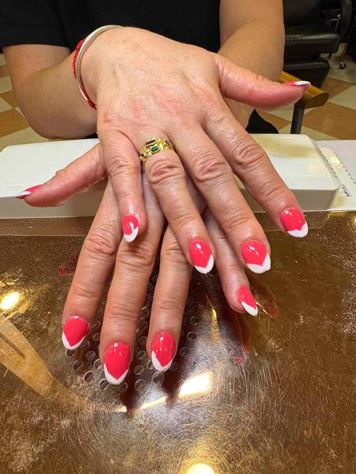 Manos con manicura francesa de color rosa brillante descansando sobre una mesa dorada brillante.