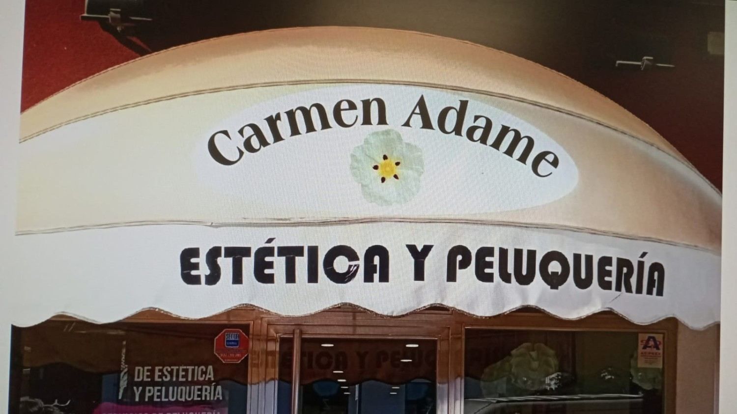 Storefront sign for “Carmen Adame” and “ESTÉTICA Y PELUQUERÍA” on a cream and red awning