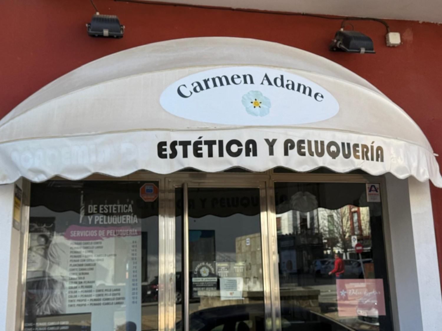 Storefront awning for Carmen Adame Estética y Peluquería on a red exterior wall