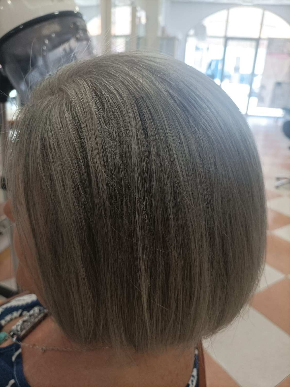 Corte de pelo bob corto y gris visto desde atrás en una silla de peluquería.