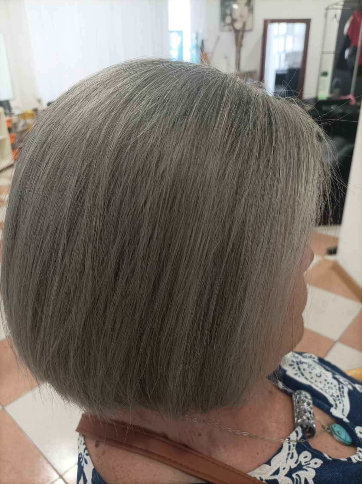 Corte de pelo bob corto y gris visto desde atrás en una silla de peluquería.