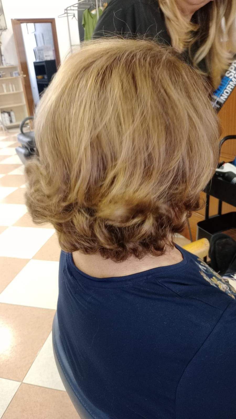 Corte de pelo corto a capas, rubio y castaño, visto desde atrás en una peluquería.