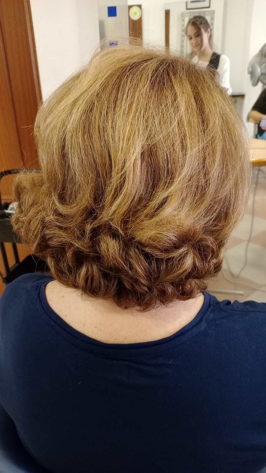 Vista posterior de cabello rubio-castaño corto en capas en un salón de belleza o aula.
