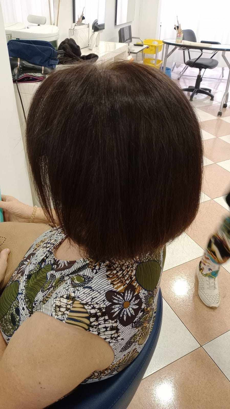 Corte de pelo bob corto castaño oscuro visto desde atrás en una silla de peluquería.