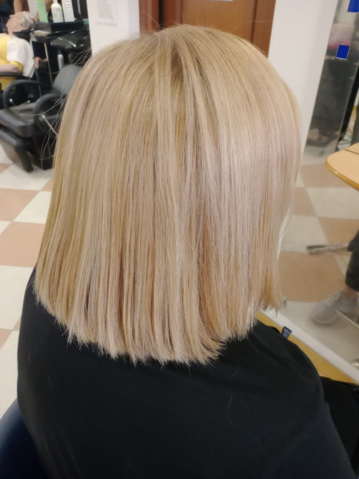 Corte bob rubio con puntas rectas, visto desde atrás en una silla de peluquería.