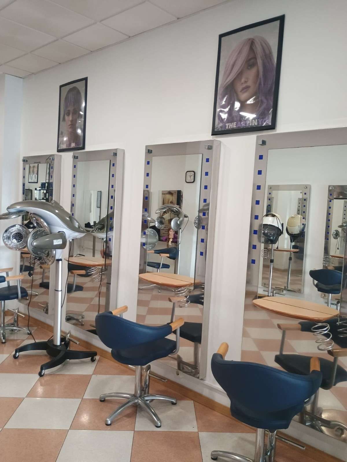 Interior de una peluquería con espejos, sillones de peluquería y secador de pelo con capucha.