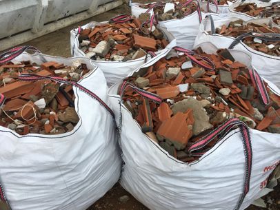 Bolsas blancas llenas de ladrillos rojos rotos y escombros de hormigón.