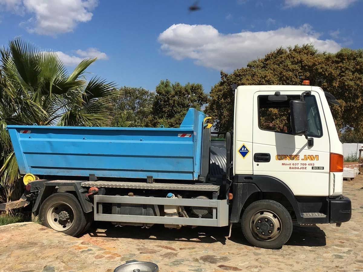 Camión volquete azul estacionado al aire libre en un día soleado.