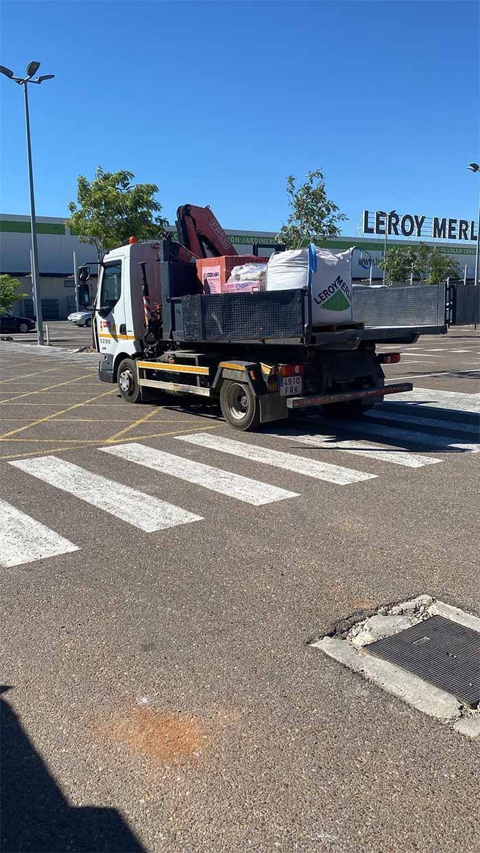 Camión con grúa en un paso de peatones frente a un edificio rotulado 