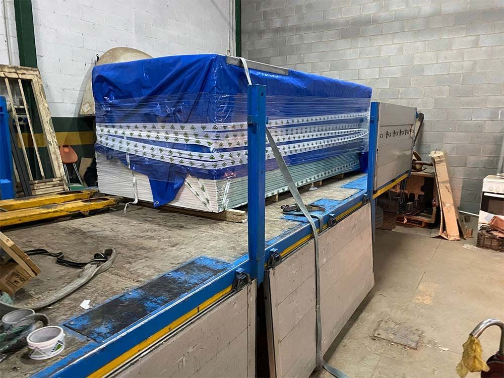 Gran máquina industrial cubierta con una lona azul, en un entorno de taller.