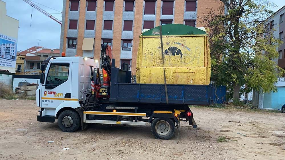 Camión que transporta un edificio portátil de color amarillo; el entorno es una zona urbana con edificios y equipos de construcción.