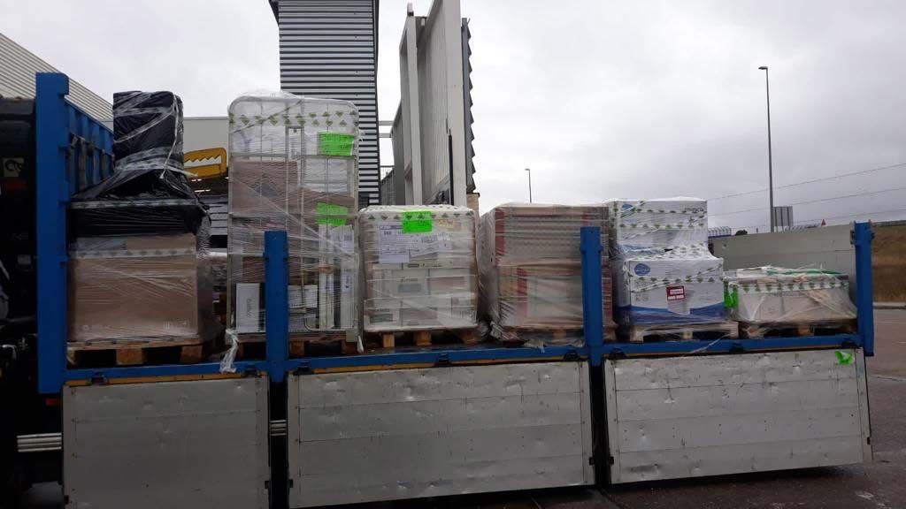 Plataforma de camión cargada con pallets de carga envueltos al aire libre bajo un cielo nublado.