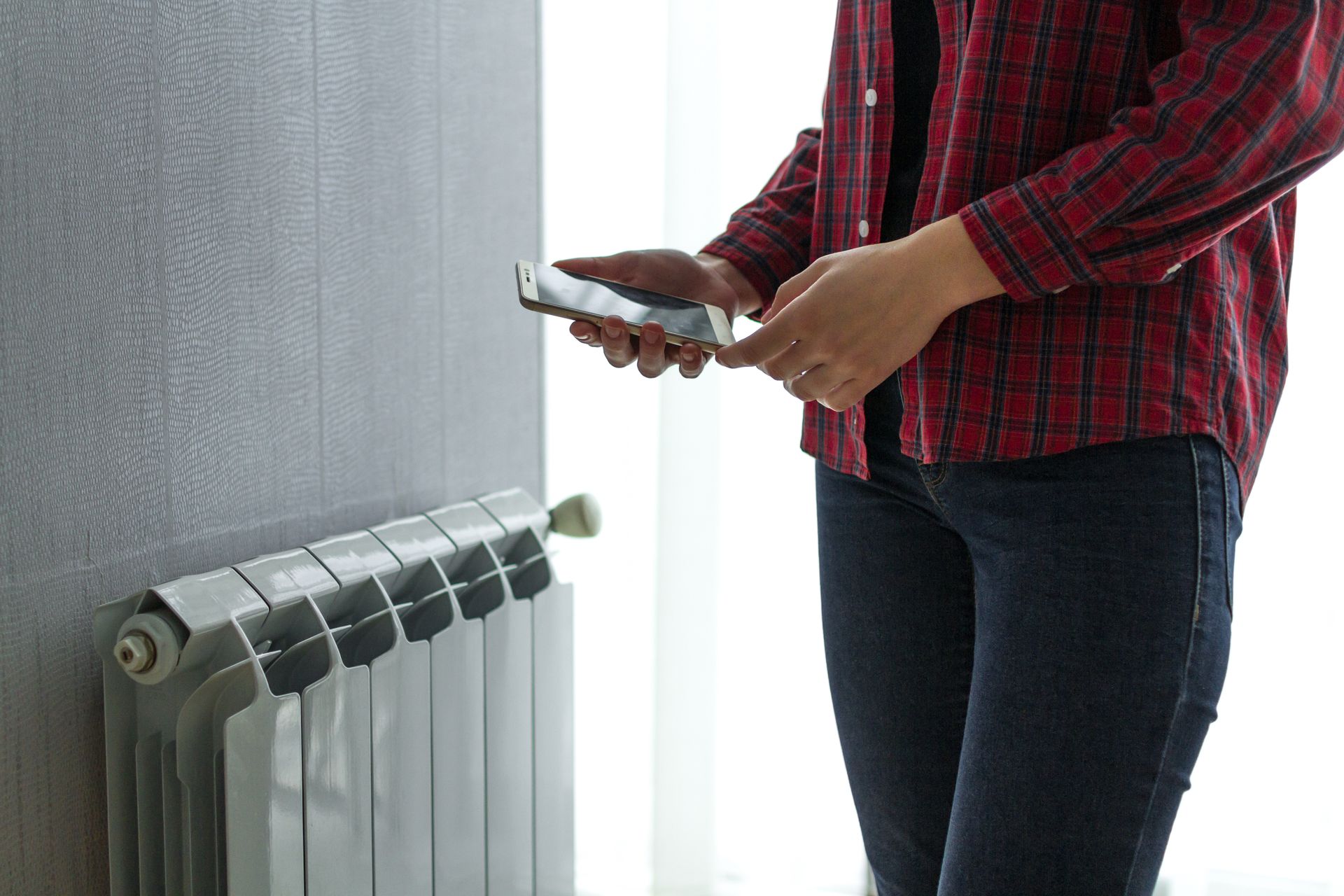 Personne contrôlant la température d'un radiateur avec son téléphone