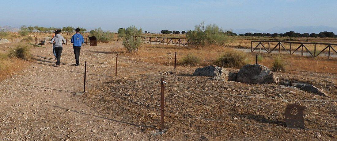 Un grupo de personas está de pie en la parte superior de un camino de tierra mirando el paisaje.