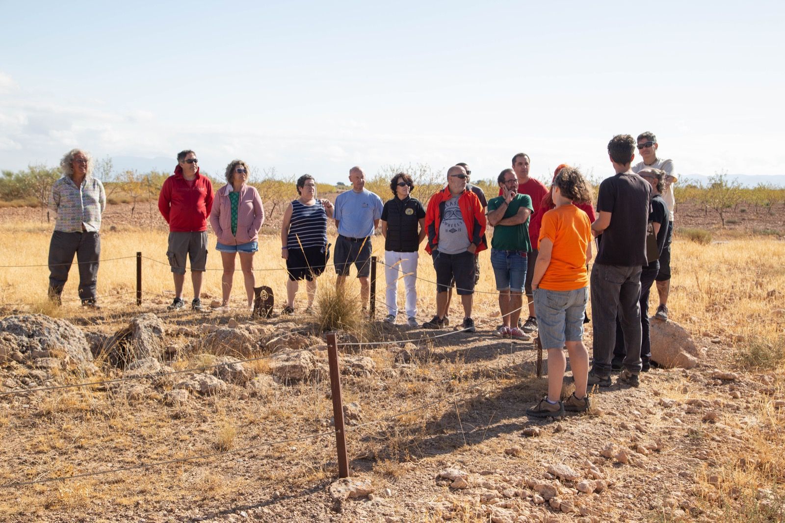 Un grupo de personas están de pie en un campo hablando entre sí.