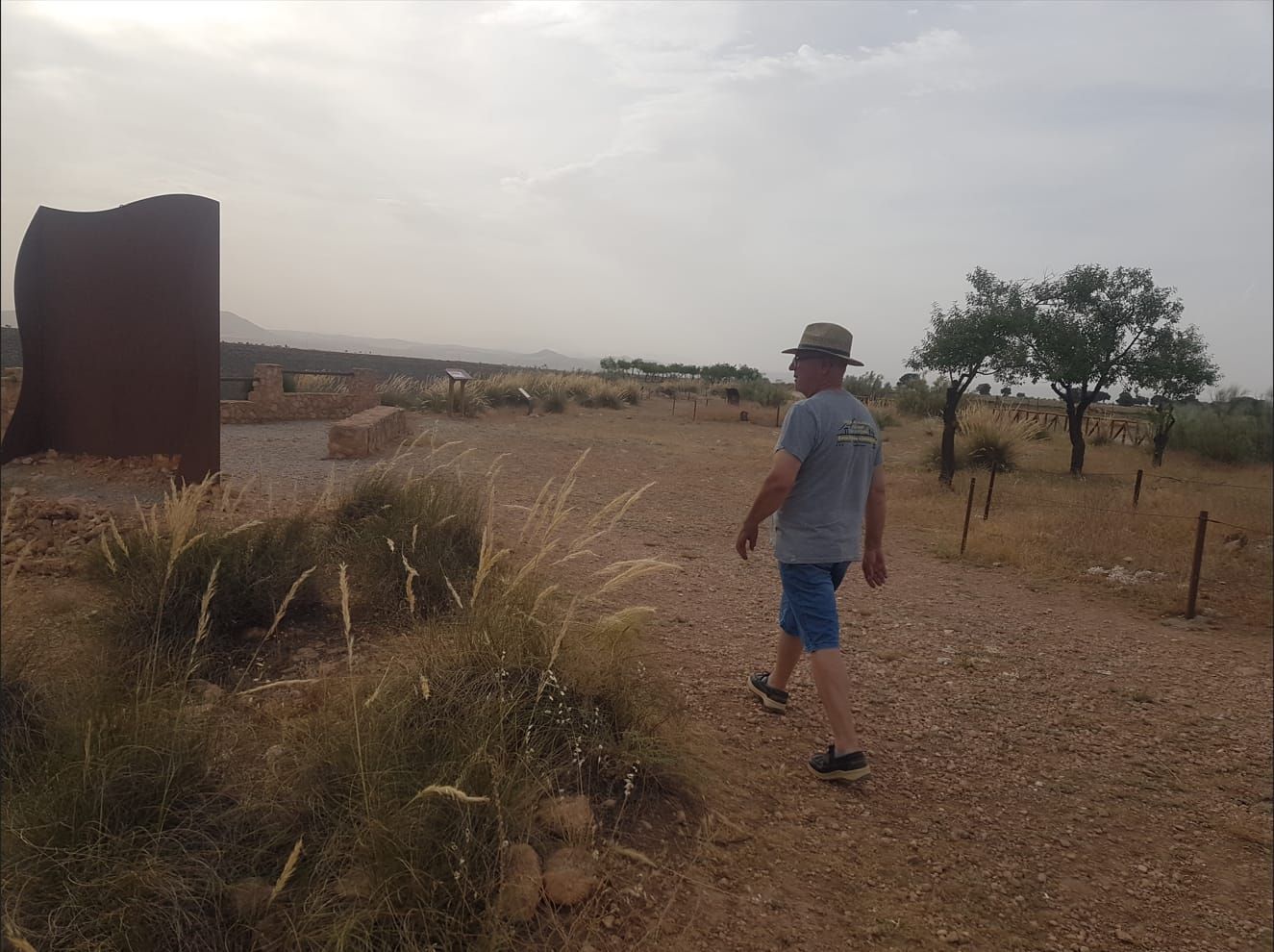 Un hombre con sombrero camina por un campo de tierra.