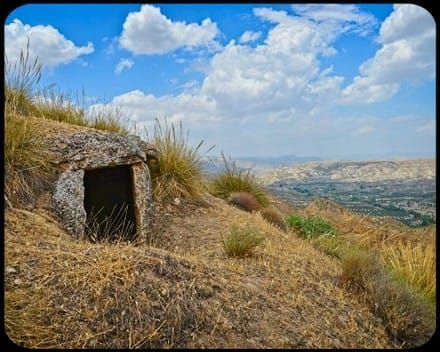 Una pequeña cueva en la cima de una colina con vistas a una ciudad.