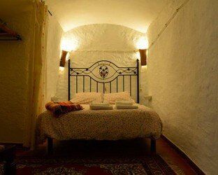 Hay una cama en una habitación pequeña con cabecera de hierro forjado.