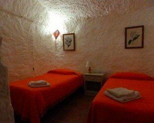 Un dormitorio con dos camas, una mesita de noche y una lámpara.