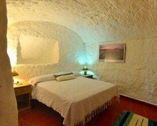 Un dormitorio en una cueva con una cama y un cuadro en la pared.