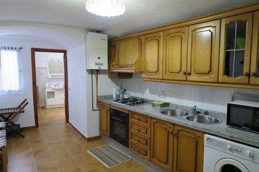 Una cocina con gabinetes de madera, una estufa, un fregadero y una lavadora y secadora.