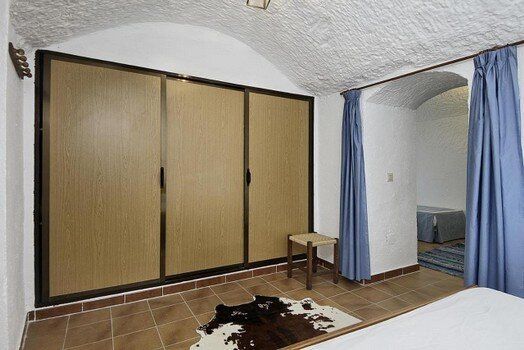 Un dormitorio con una cama, armario, silla y cortinas azules.