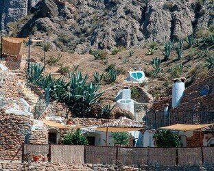 Un edificio de piedra con sombrillas frente a una montaña.