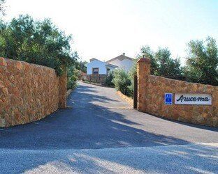 Un muro de piedra al costado de un camino que conduce a una casa.
