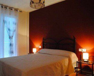 Un dormitorio con una cama, dos lámparas y una ventana.