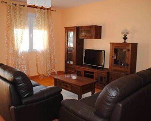 Una sala de estar con sofá, silla, mesa de café y televisión.