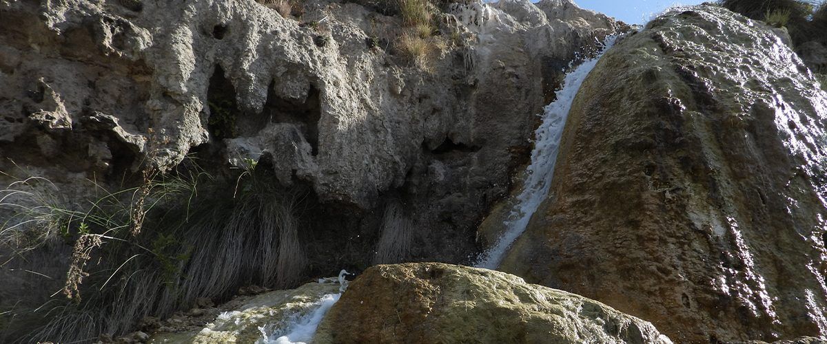 Una cascada está rodeada de rocas en medio de un bosque.