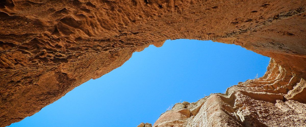 Mirando desde una cueva hacia un cielo azul.