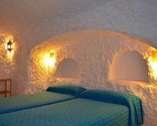 Un dormitorio con dos camas y una pared de piedra.