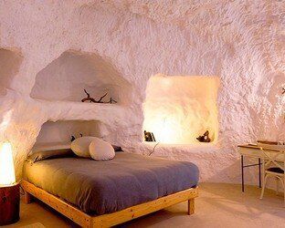 Un dormitorio con una cama y un escritorio en una cueva.