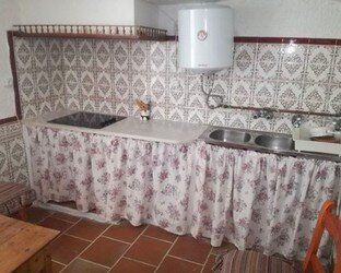 Una cocina con fregadero, estufa y cortinas florales.
