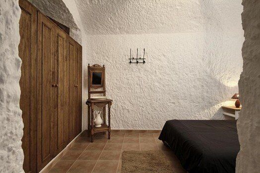 Un dormitorio con una cama, una silla y armarios.