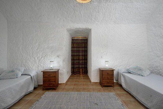 Un dormitorio con dos camas, dos mesitas de noche y una alfombra.