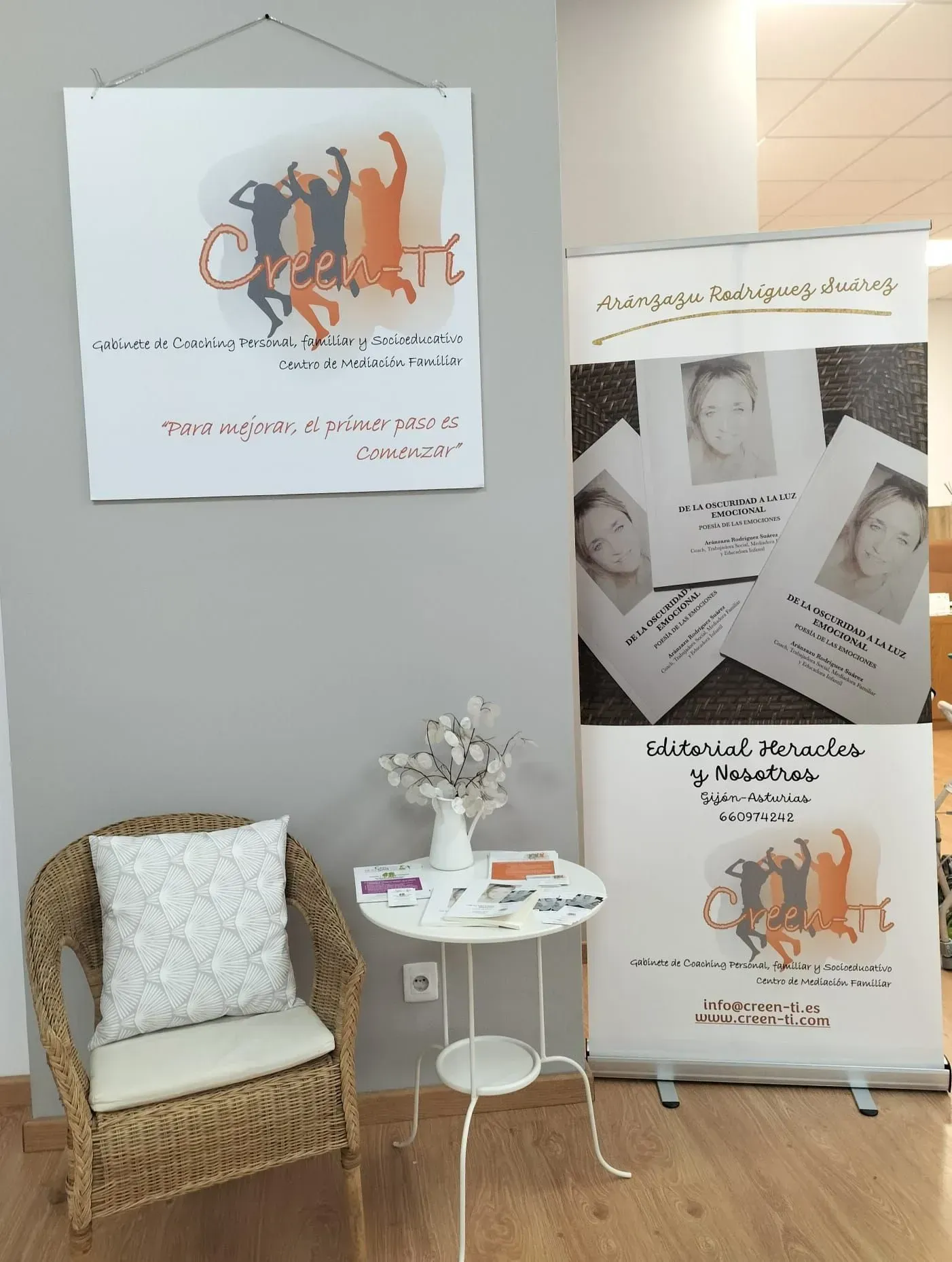 Una pequeña sala de espera con una silla, una mesa pequeña y carteles informativos en una pared.