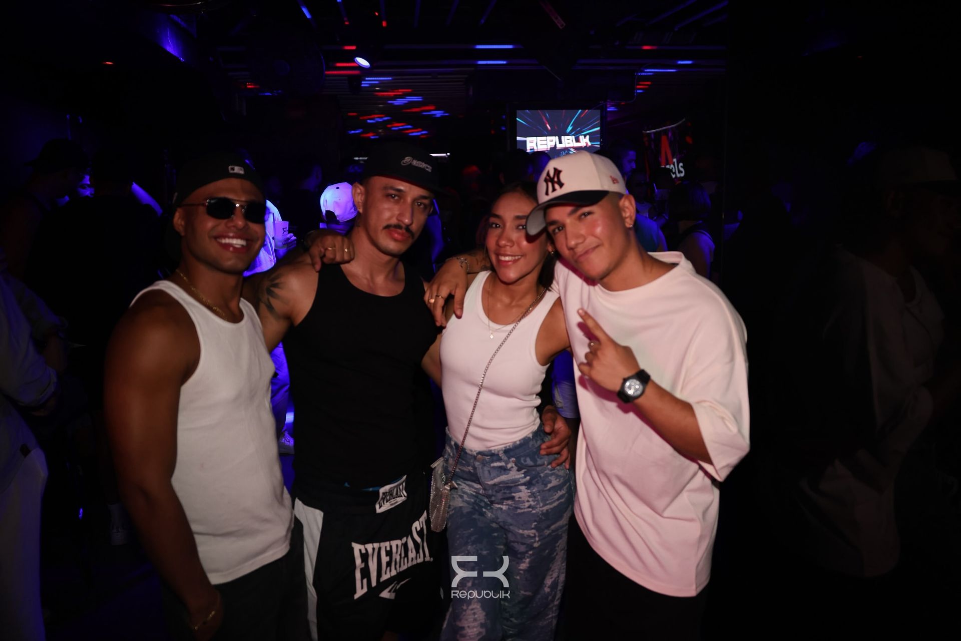 Cuatro amigos posando juntos en una discoteca oscura con luces de neón