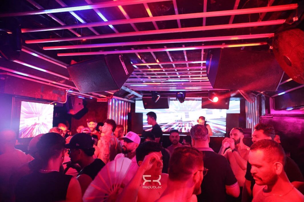 Discoteca abarrotada con gente bailando bajo luces de neón rojas y moradas