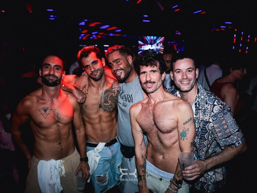 Dos personas sonrientes sosteniendo bebidas en una discoteca con luces de neón de colores