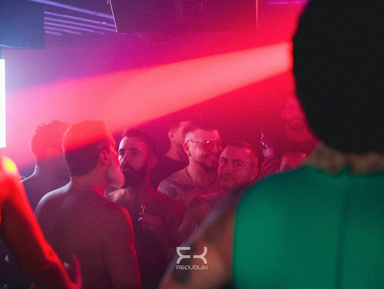 Discoteca abarrotada, con luces rojas y moradas y gente bailando en una sala llena de humo