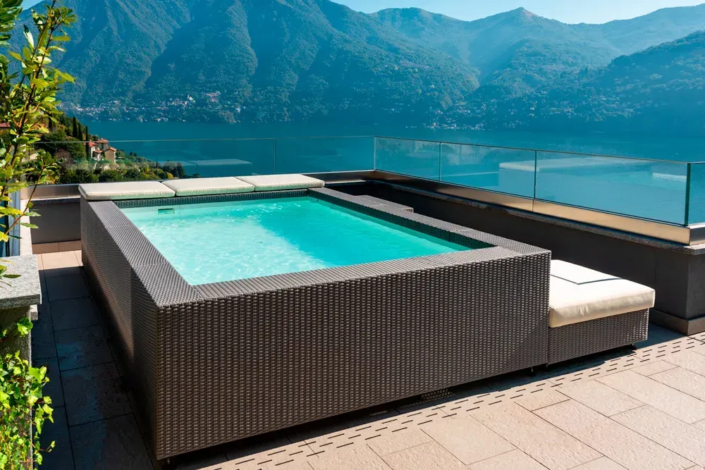 Una piscina sul tetto con vista su un lago e montagne sullo sfondo.