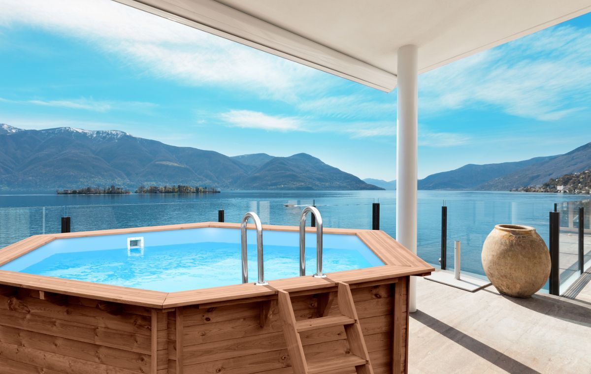 Una piscina di legno su un balcone con vista sul lago.