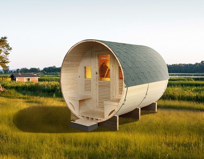 Una botte di legno con il tetto verde si trova in mezzo a un campo erboso.