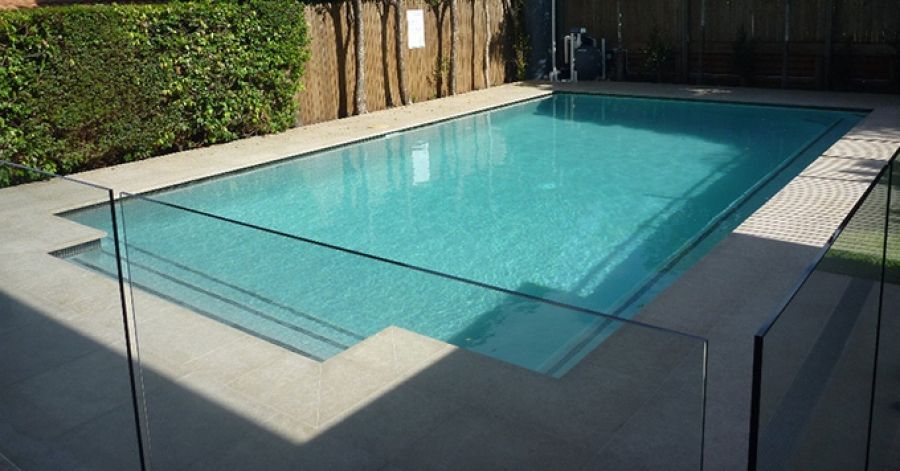 Una grande piscina è circondata da una recinzione in vetro.