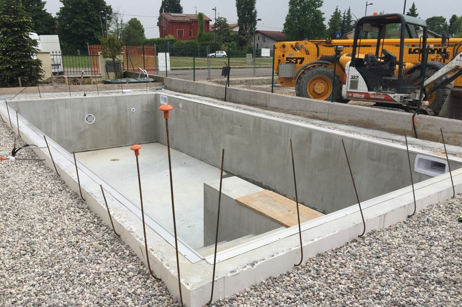 Si sta costruendo una grande piscina in cemento con una ruspa sullo sfondo.