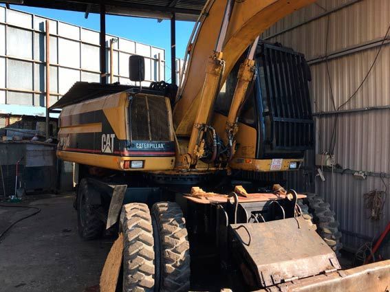 Una gran excavadora amarilla está estacionada en un garaje.
