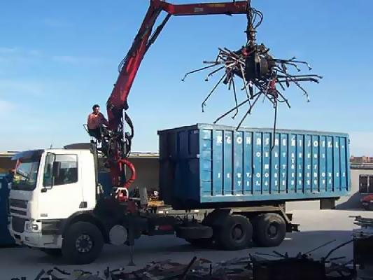 Un camión con una grúa acoplada transporta un contenedor azul.