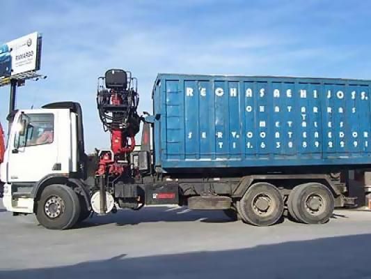 Un camión blanco con un contenedor azul en la parte trasera está estacionado al costado de la carretera.